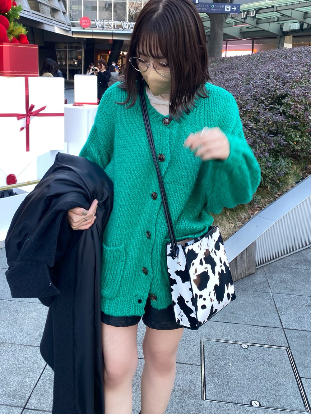 ホワイト系のショルダーバッグ、ブラック系のブーツ、グレー系のステンカラーコートを着用したレディースの冬コーディネートの2枚目の写真