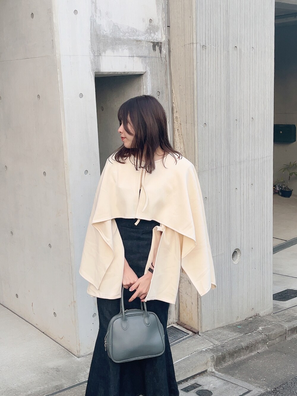 グレー系のボストンバッグ、ホワイト系のブーツ、ブルー系のサロペット/オーバーオールを着用したレディースの春コーディネートの2枚目の写真