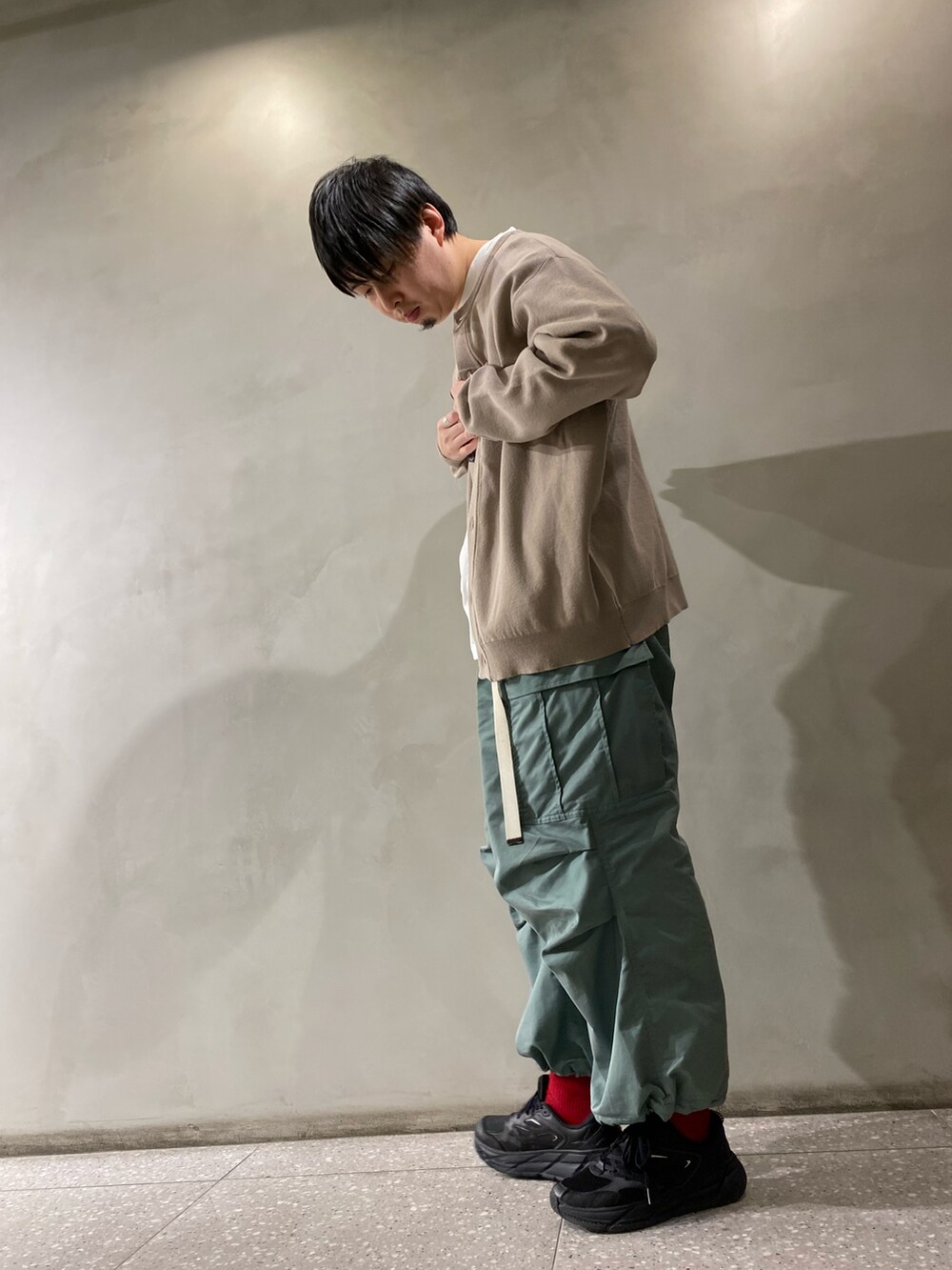 グリーン系のカーゴパンツ、ブラック系のスニーカーを着用したメンズの春コーディネートの2枚目の写真