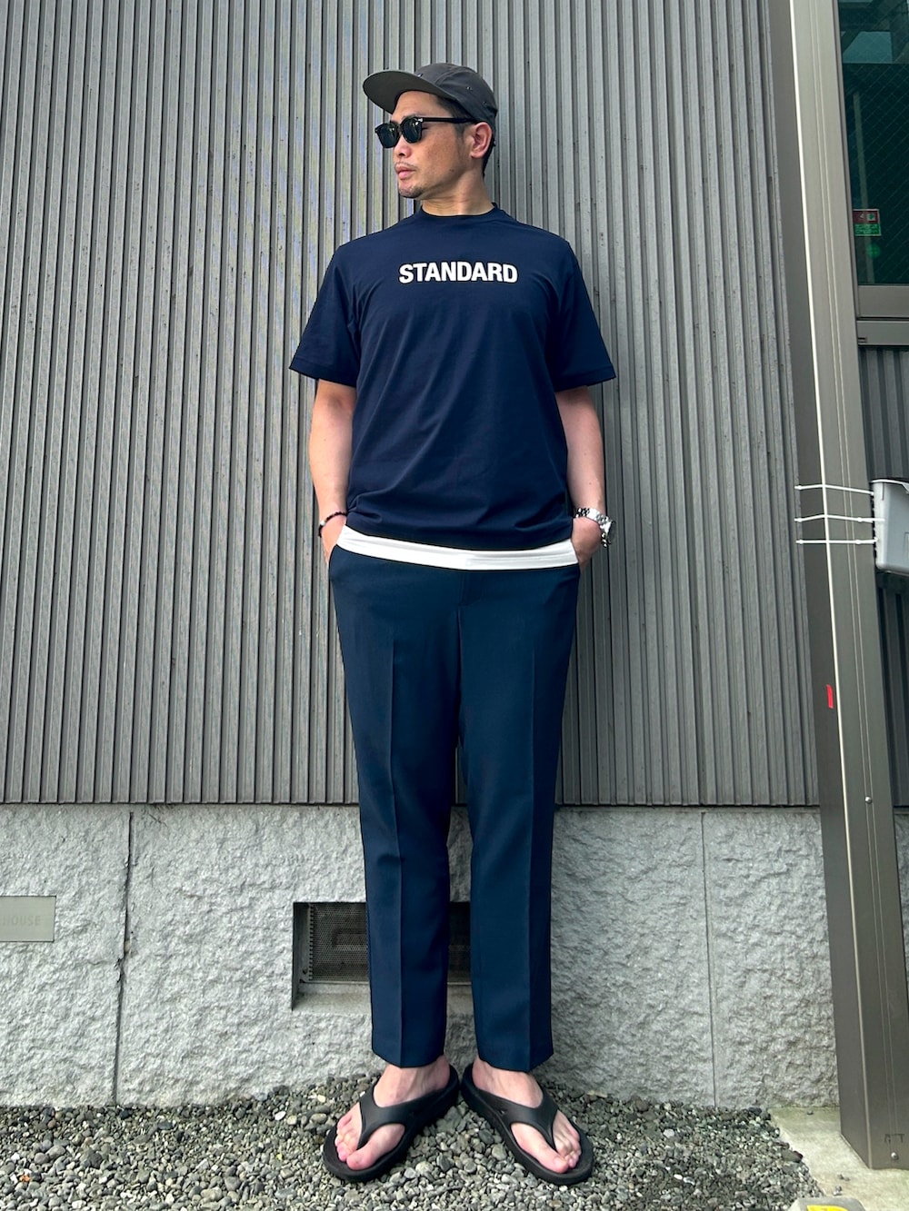 ブルー系のTシャツ/カットソー、ブルー系のスラックス、ブラック系のサンダルを着用したメンズの夏コーディネートの2枚目の写真