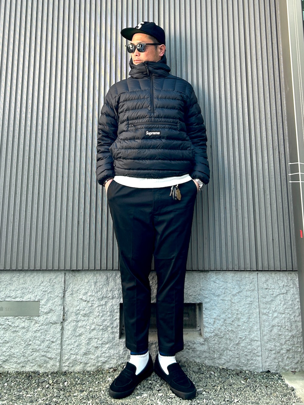 ブラック系のスニーカー、ホワイト系のTシャツ/カットソー、ブラック系のダウンジャケット/コートを着用したメンズの春コーディネートの3枚目の写真