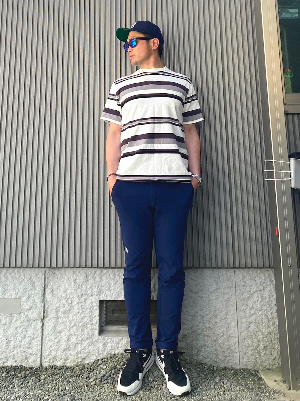 ブラック系のTシャツ/カットソー、ブルー系のチノパンツ、ブラック系のスニーカーを着用したメンズの春コーディネートの3枚目の写真