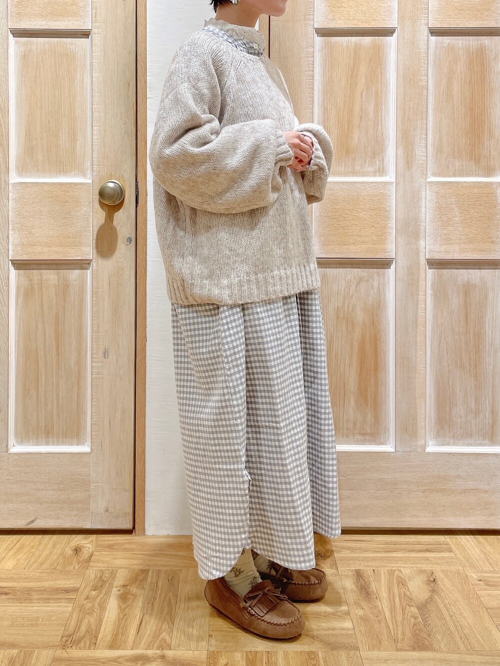 ホワイト系のTシャツ/カットソー、ベージュ系のニット/セーター、ホワイト系のエコバッグ/サブバッグを着用したレディースの冬コーディネートの2枚目の写真