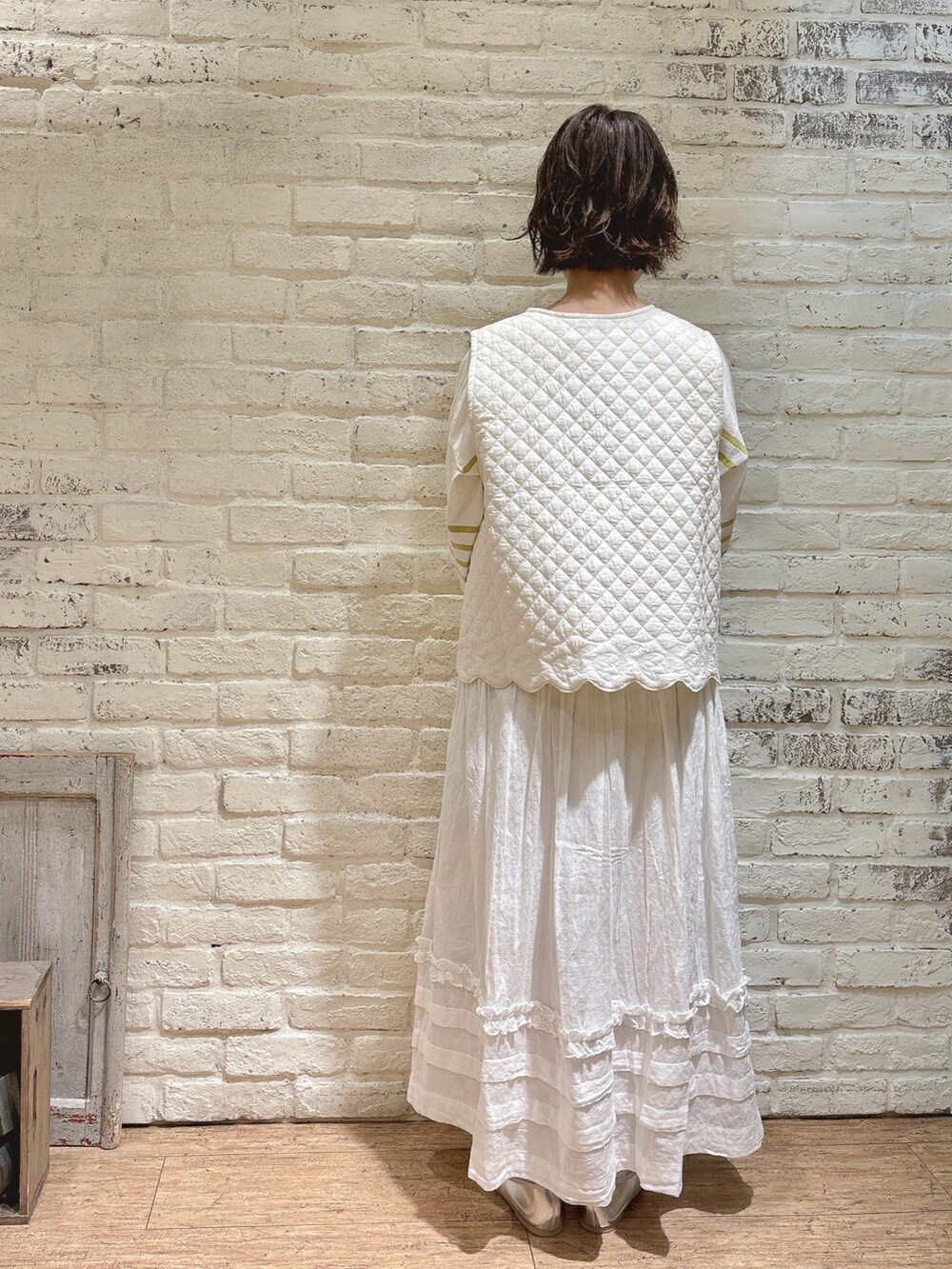 イエロー系のTシャツ/カットソー、ホワイト系のベスト、ホワイト系のスカートを着用したレディースの春コーディネートの3枚目の写真