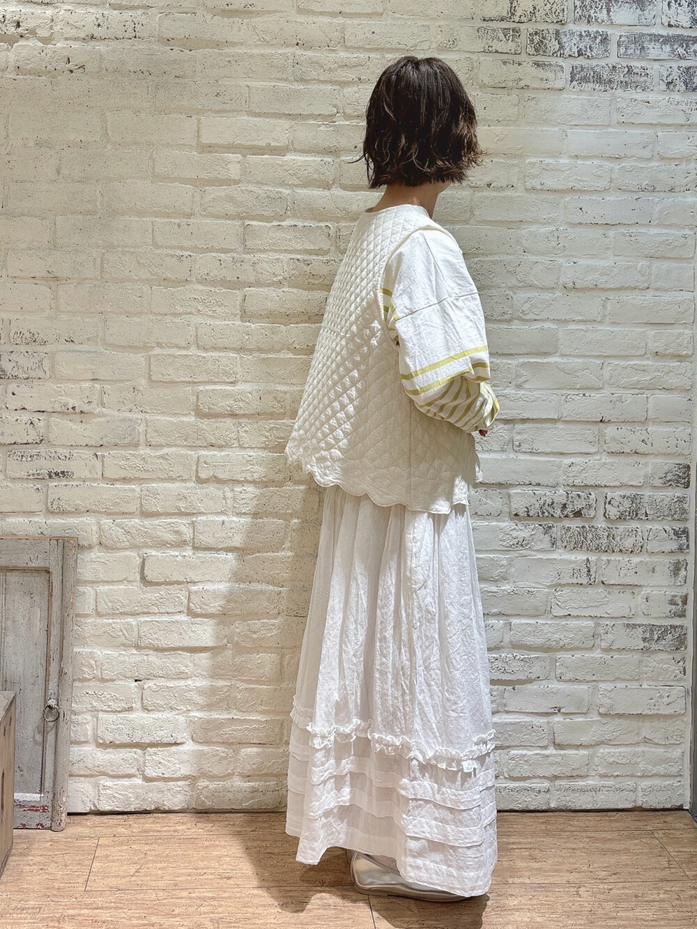 イエロー系のTシャツ/カットソー、ホワイト系のベスト、ホワイト系のスカートを着用したレディースの春コーディネートの2枚目の写真