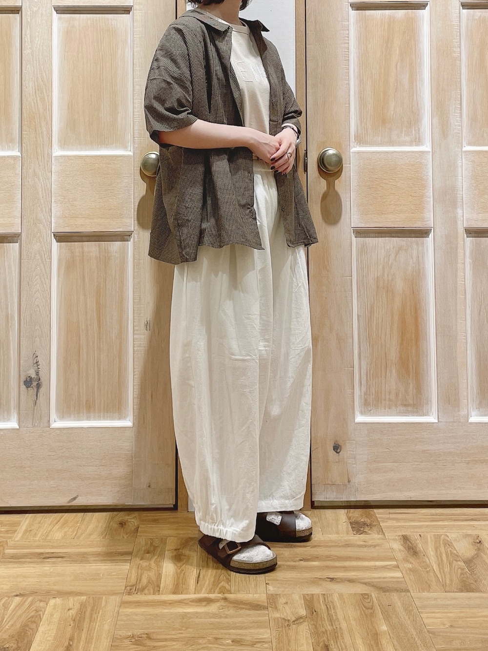 ベージュ系のTシャツ/カットソー、ホワイト系のその他パンツ、ブラウン系のサンダルを着用したレディースの夏コーディネートの2枚目の写真
