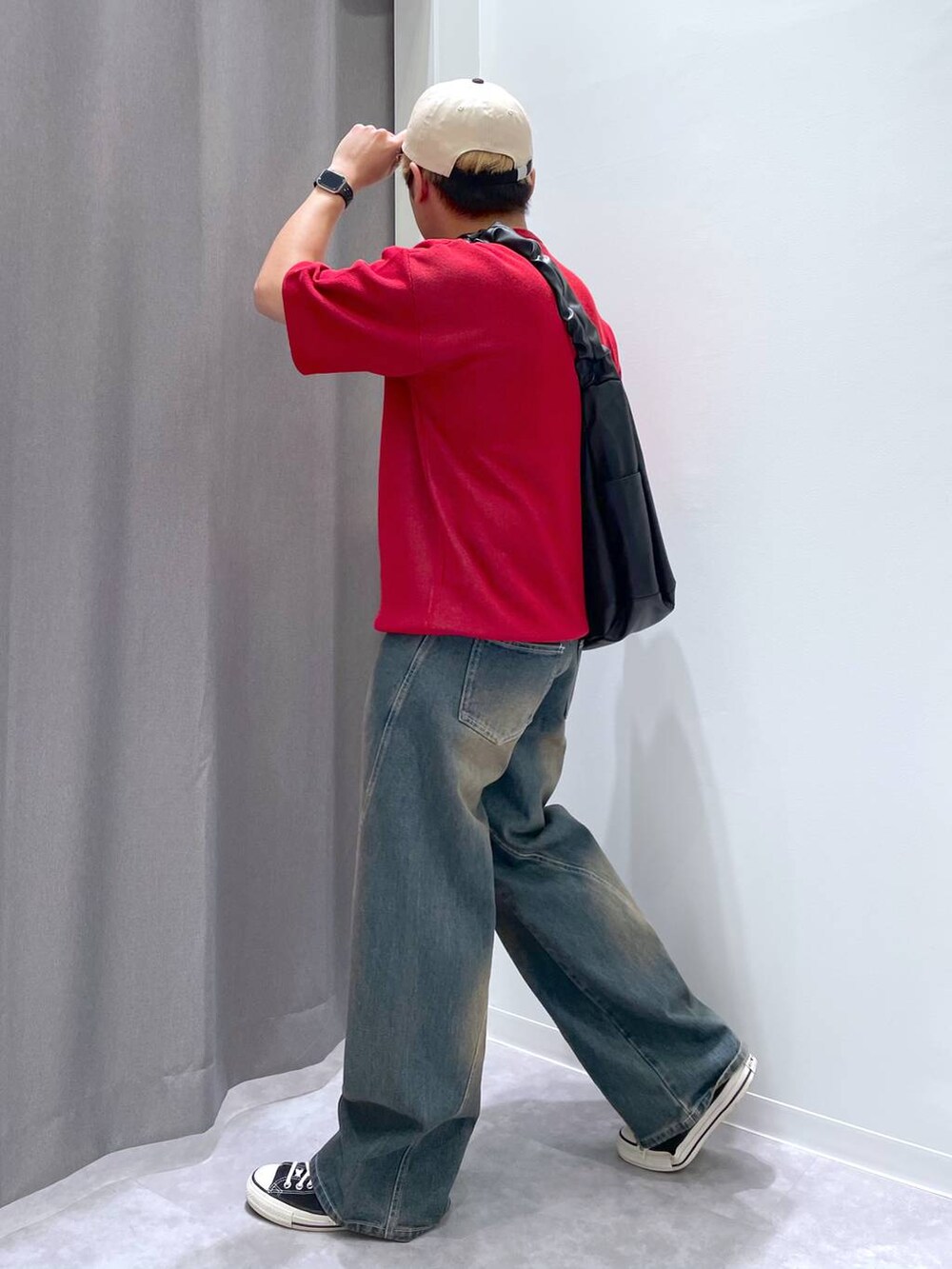 ブルー系のデニムパンツ、ブラック系のショルダーバッグ、レッド系のニット/セーターを着用したメンズの春コーディネートの5枚目の写真