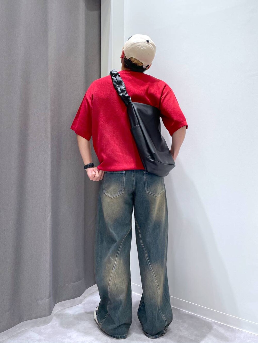 ブルー系のデニムパンツ、ブラック系のショルダーバッグ、レッド系のニット/セーターを着用したメンズの春コーディネートの2枚目の写真