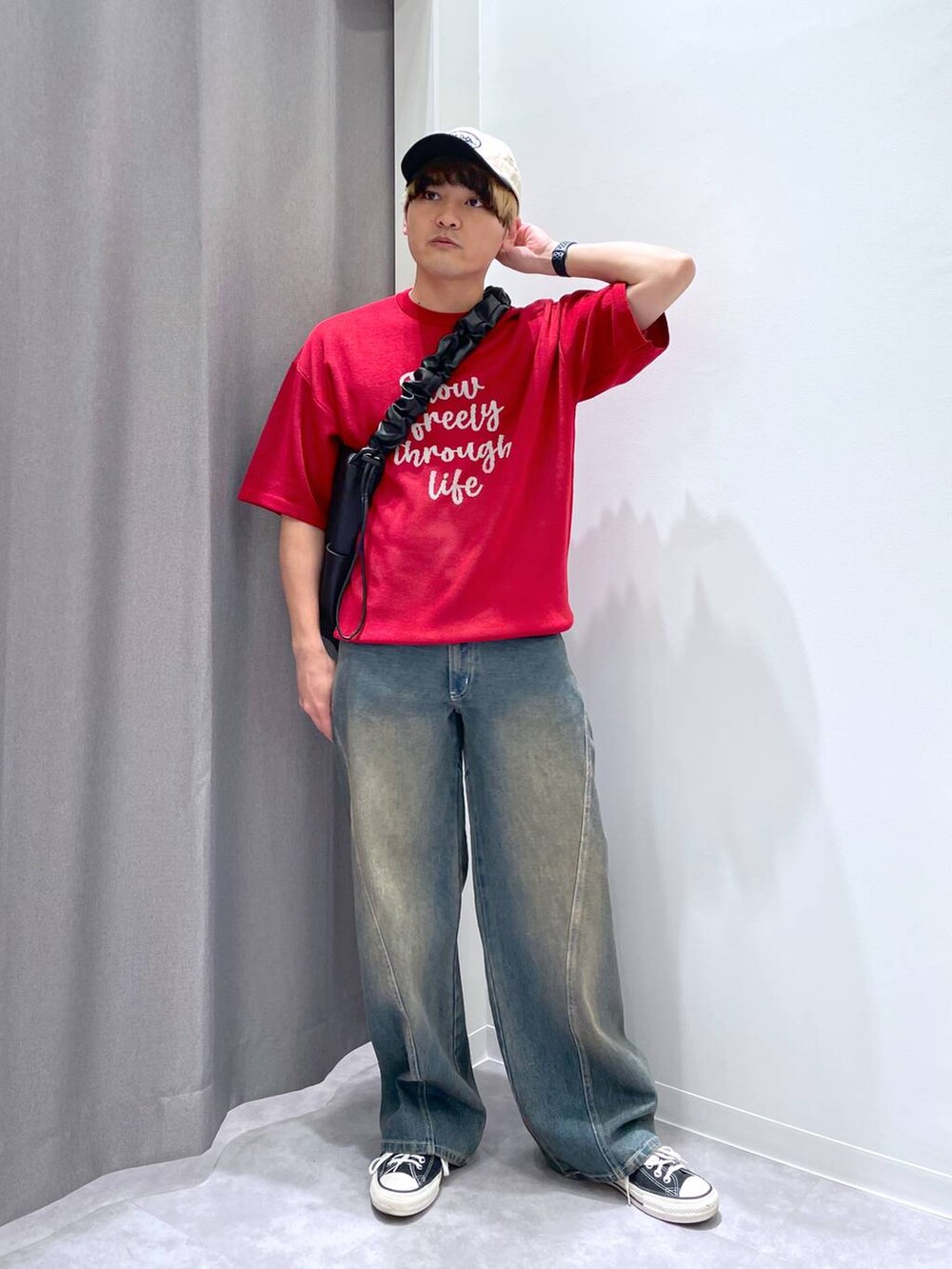 ブルー系のデニムパンツ、ブラック系のショルダーバッグ、レッド系のニット/セーターを着用したメンズの春コーディネートの6枚目の写真
