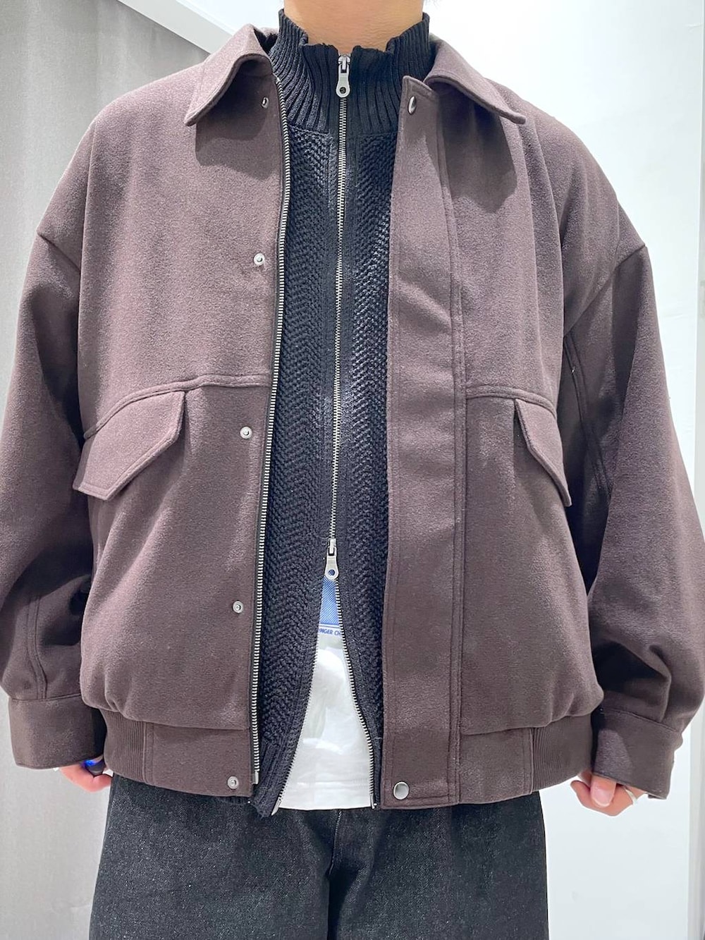 ブラウン系のブルゾン、ブラック系のデニムパンツ、ブラック系のニット/セーターを着用したメンズの秋コーディネートの5枚目の写真