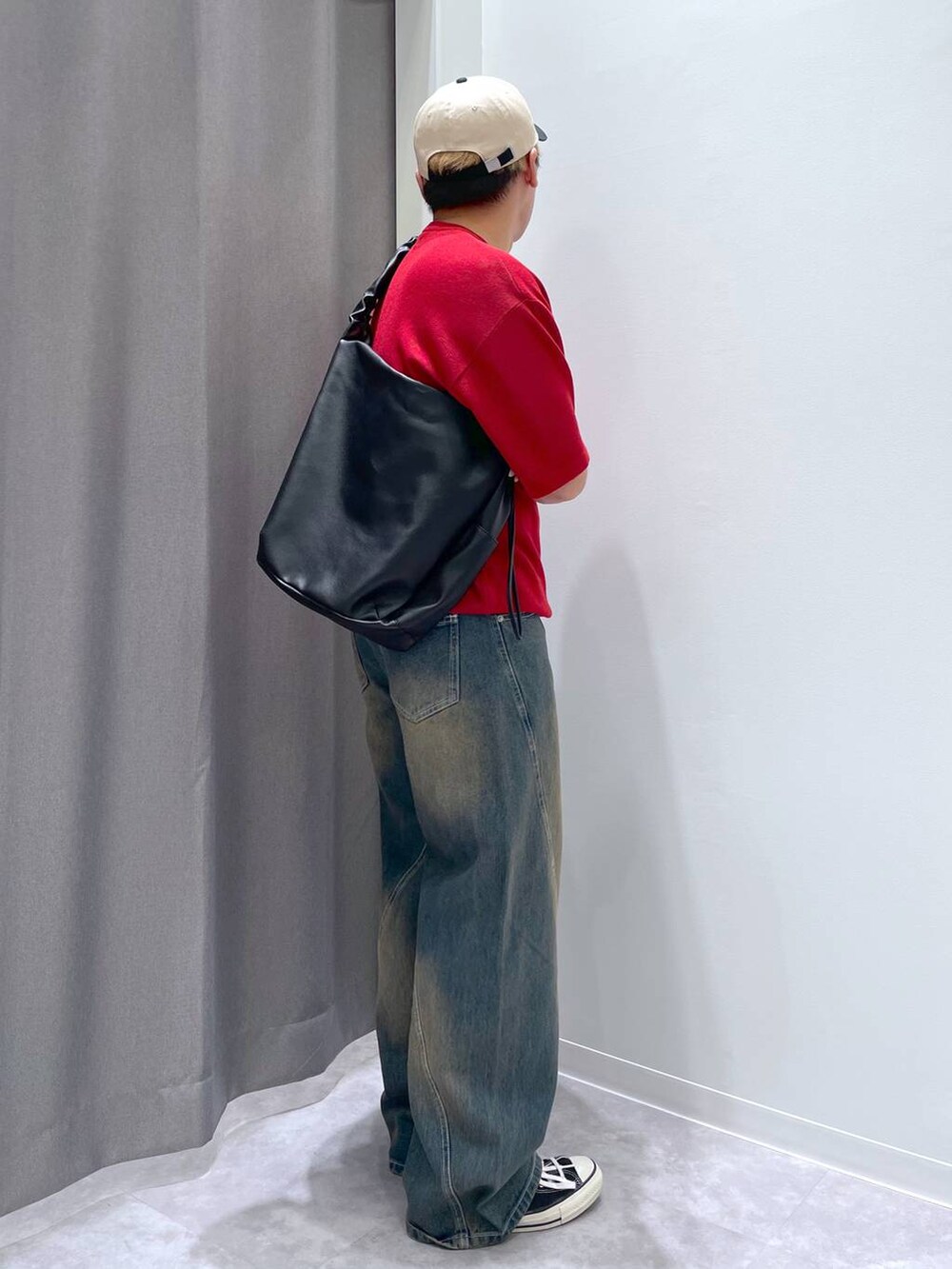 ブルー系のデニムパンツ、ブラック系のショルダーバッグ、レッド系のニット/セーターを着用したメンズの春コーディネートの3枚目の写真