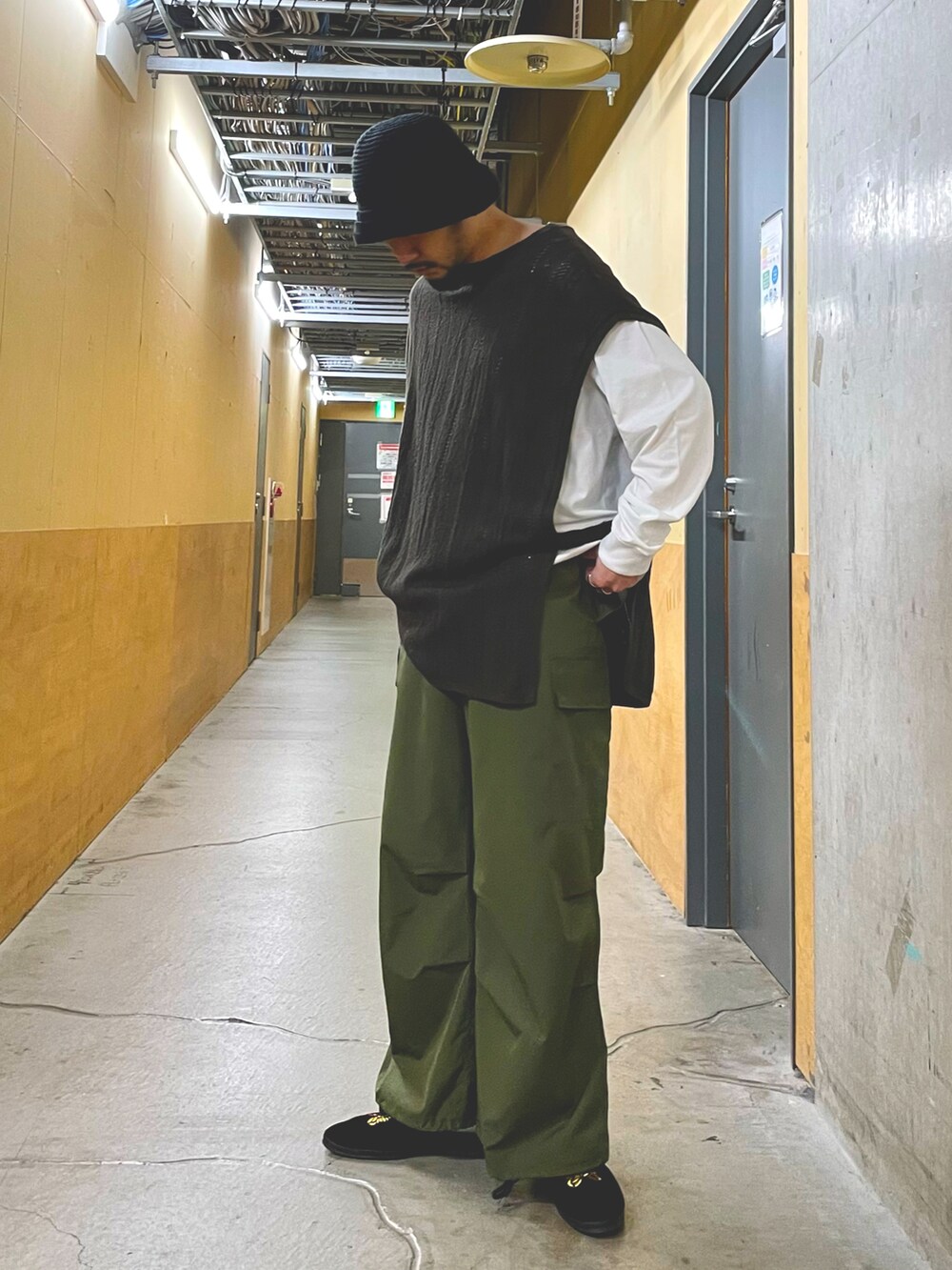 グリーン系のカーゴパンツ、ホワイト系のTシャツ/カットソー、ブラウン系のベストを着用したメンズの春コーディネートの2枚目の写真