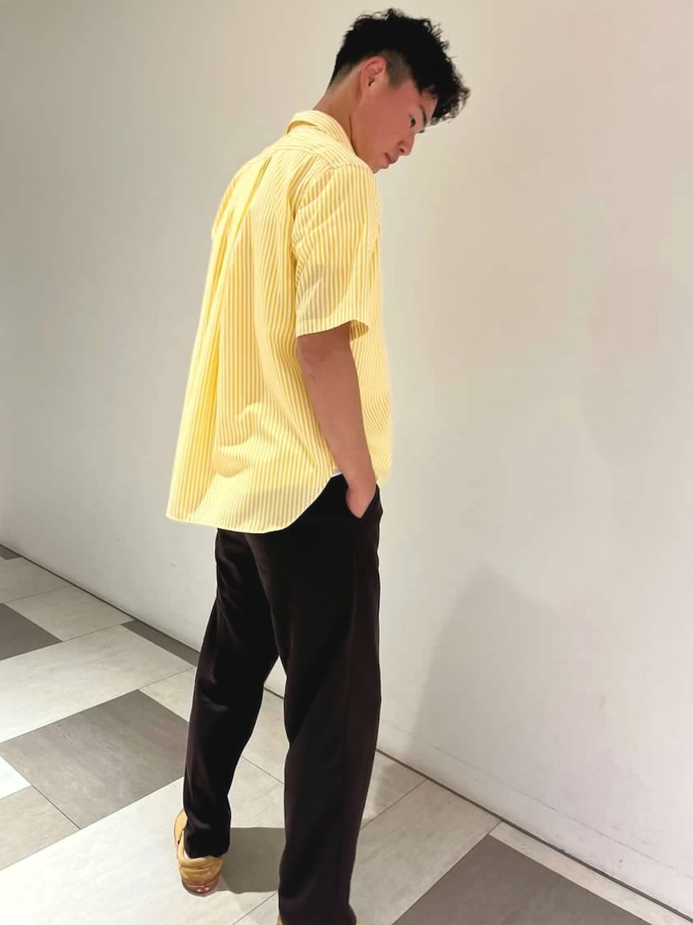 ブラウン系のスラックス、ホワイト系のTシャツ/カットソー、イエロー系のシャツ/ブラウスを着用したメンズの夏コーディネートの2枚目の写真