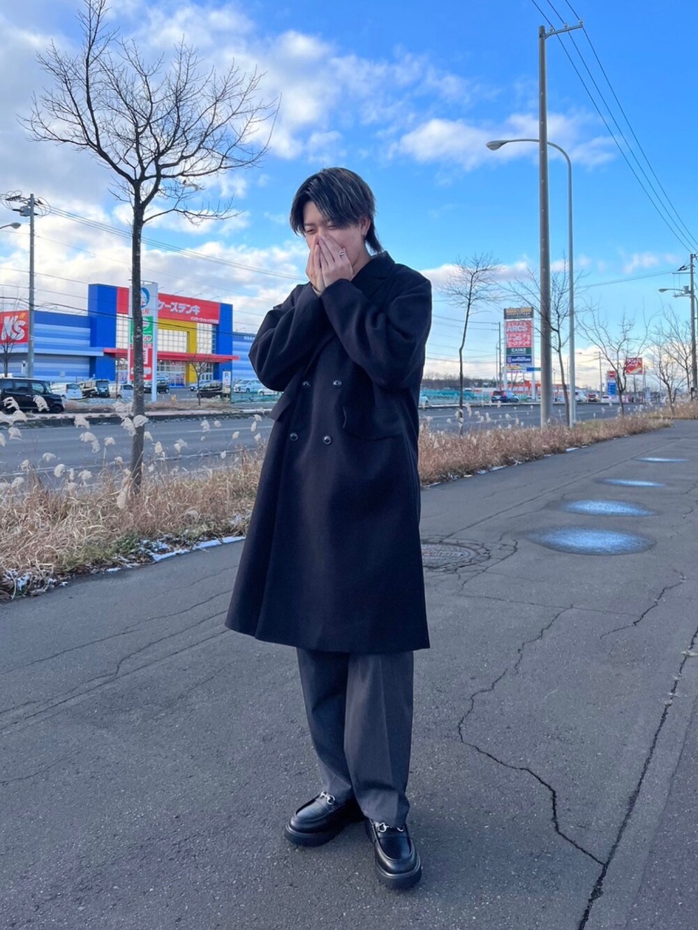 ブラック系のチェスターコート、グレー系のスラックス、ブラック系のローファーを着用したメンズの冬コーディネートの2枚目の写真