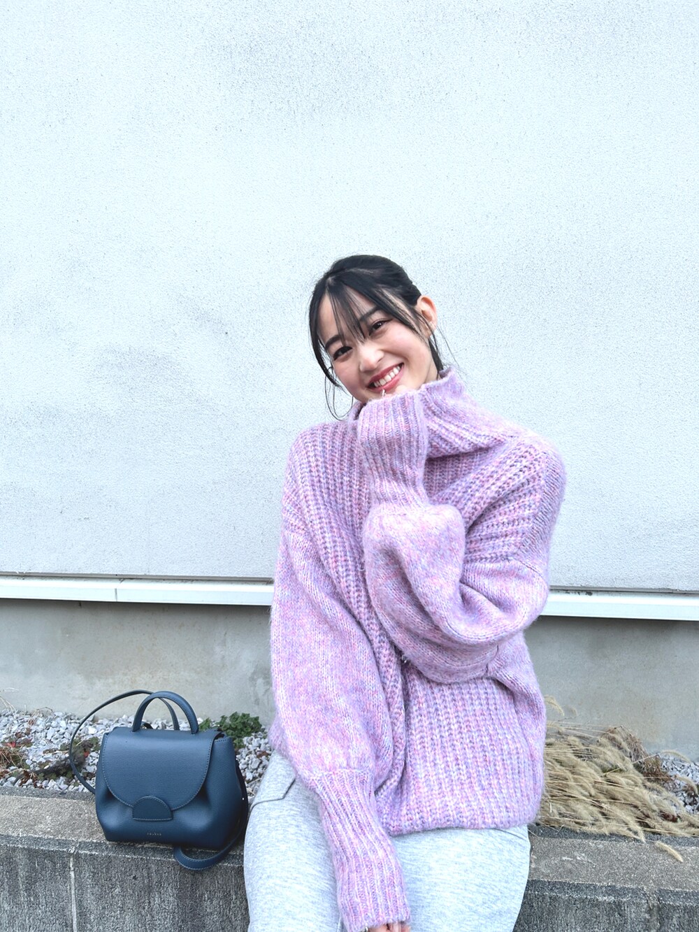 ブルー系のショルダーバッグ、ピンク系のニット/セーター、グレー系のスカートを着用したレディースの冬コーディネートの2枚目の写真