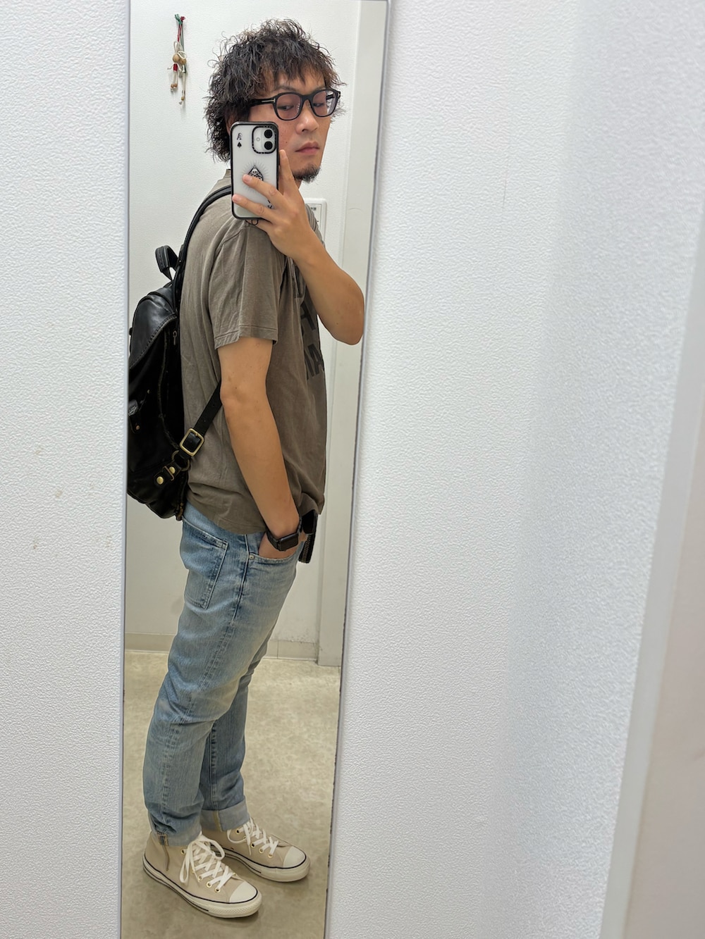 グリーン系のTシャツ/カットソー、ブルー系のデニムパンツ、ベージュ系のスニーカーを着用したメンズの夏コーディネートの2枚目の写真