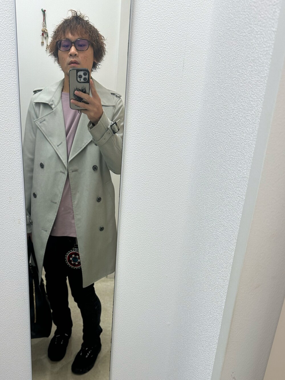 グレー系のトレンチコート、ピンク系のTシャツ/カットソー、ブラック系のデニムパンツを着用したメンズの秋コーディネートの2枚目の写真