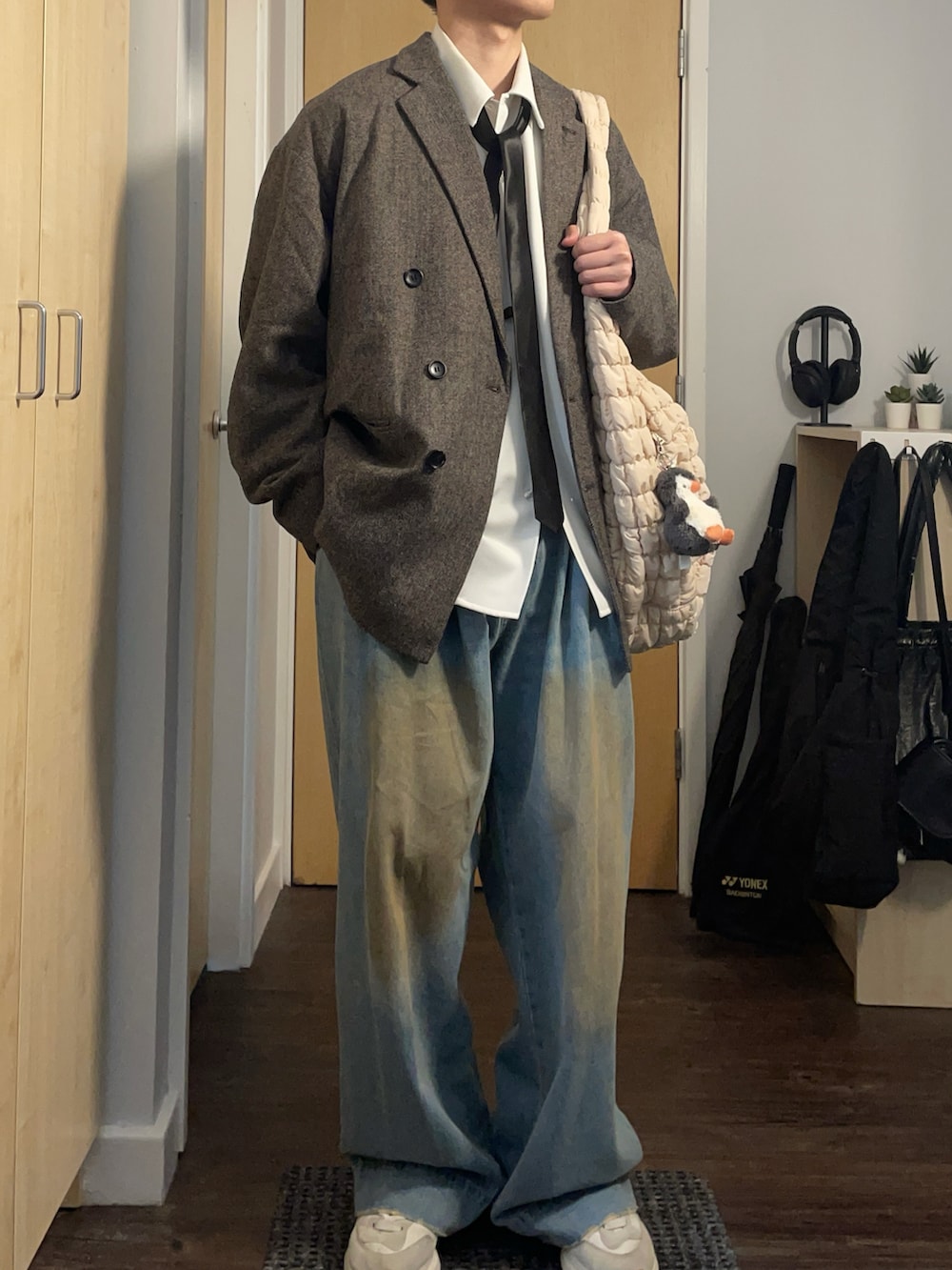 グレー系のテーラードジャケット、ホワイト系のショルダーバッグ、ブルー系のデニムパンツを着用したメンズの春コーディネートの2枚目の写真