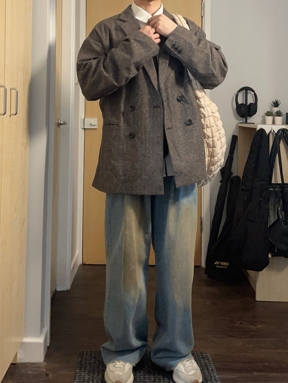 グレー系のテーラードジャケット、ホワイト系のショルダーバッグ、ブルー系のデニムパンツを着用したメンズの春コーディネートの3枚目の写真