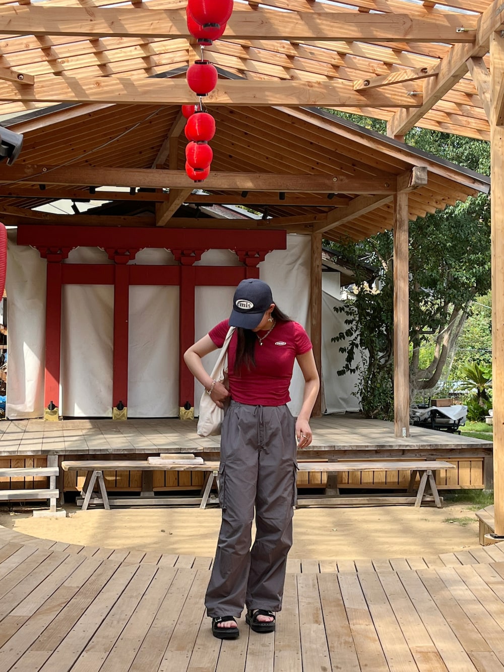 ブラック系のサンダル、レッド系のTシャツ/カットソー、グレー系のその他パンツを着用したレディースの夏コーディネートの2枚目の写真