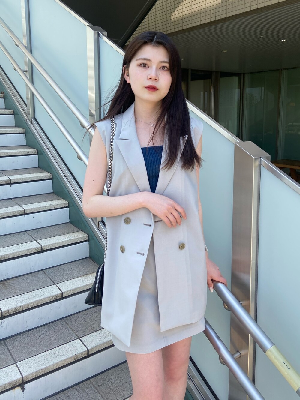 ブルー系のニット/セーター、グレー系のベスト、グレー系のスカートを着用したレディースの春コーディネートの4枚目の写真