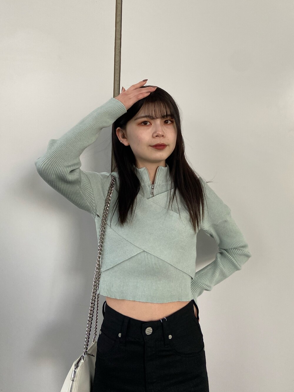 ブラック系のデニムパンツ、ブルー系のニット/セーター、ホワイト系のハンドバッグを着用したレディースの冬コーディネートの4枚目の写真