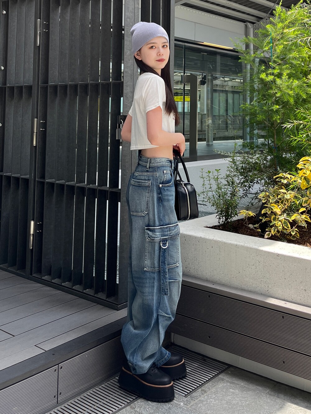 ブルー系のデニムパンツ、ホワイト系のTシャツ/カットソー、ブラック系のボストンバッグを着用したレディースの夏コーディネートの2枚目の写真