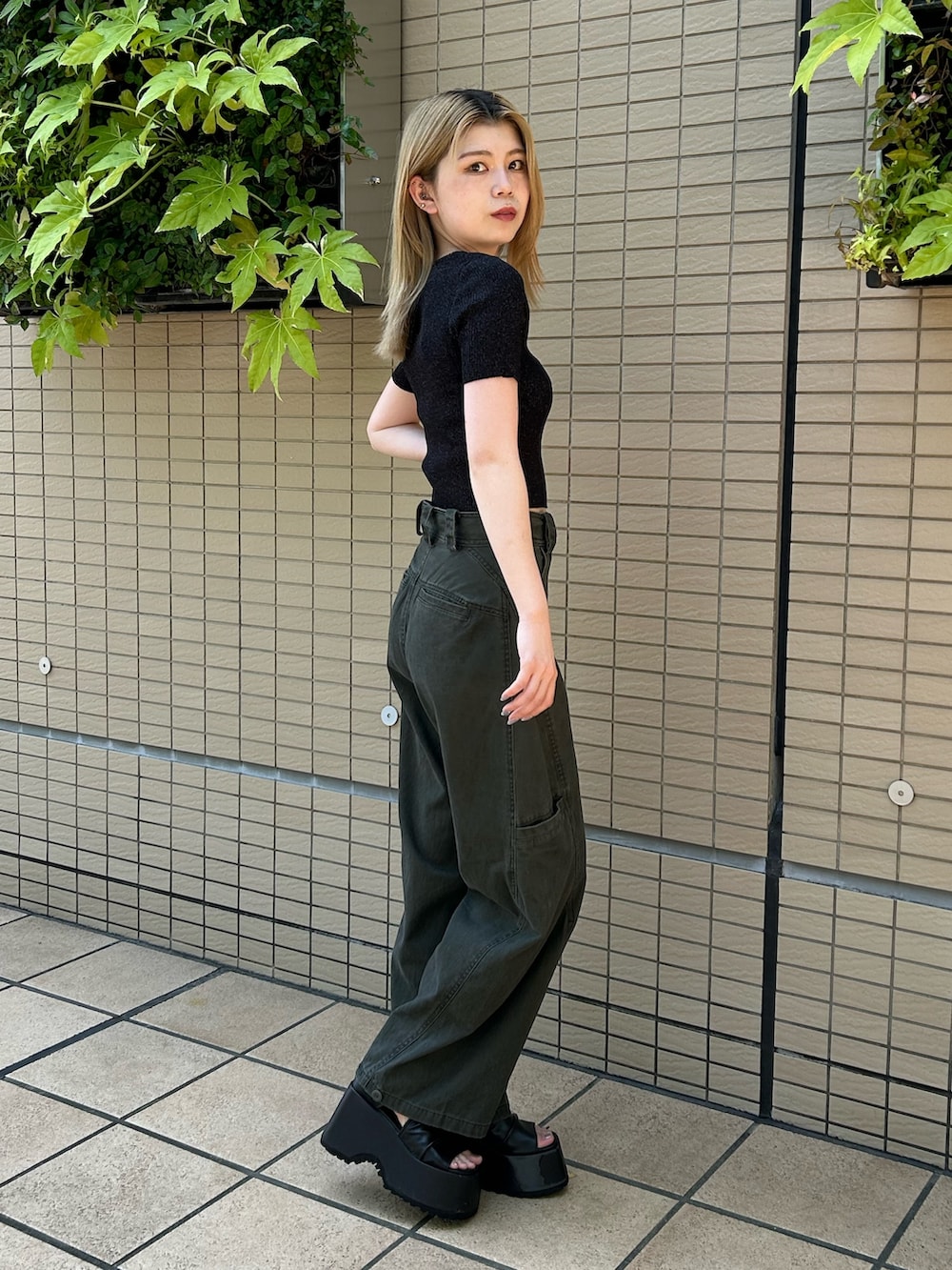 ブラック系のニット/セーター、グリーン系のその他パンツ、ブラック系のブーツを着用したレディースの夏コーディネートの2枚目の写真