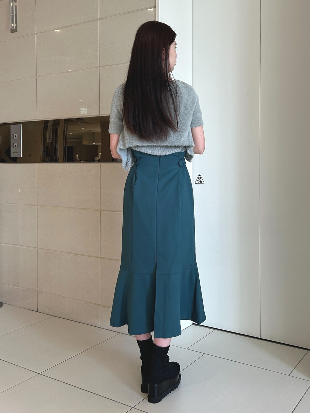 ブルー系のスカート、グレー系のニット/セーター、ブラック系のブーツを着用したレディースの秋コーディネートの2枚目の写真