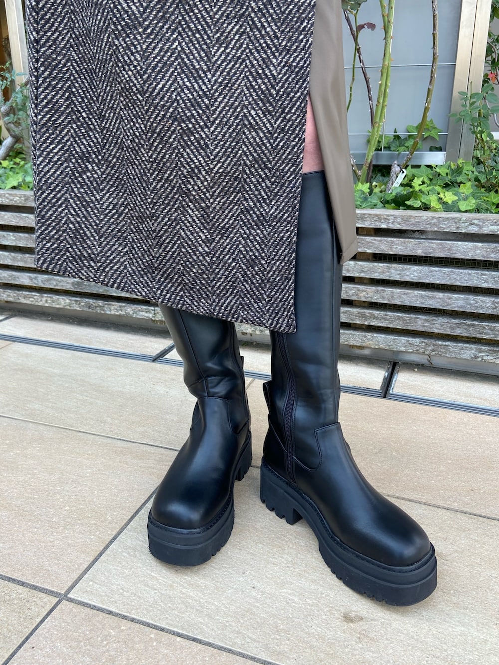 ブルー系のステンカラーコート、ベージュ系のニット/セーター、ブラウン系のスカートを着用したレディースの秋コーディネートの10枚目の写真