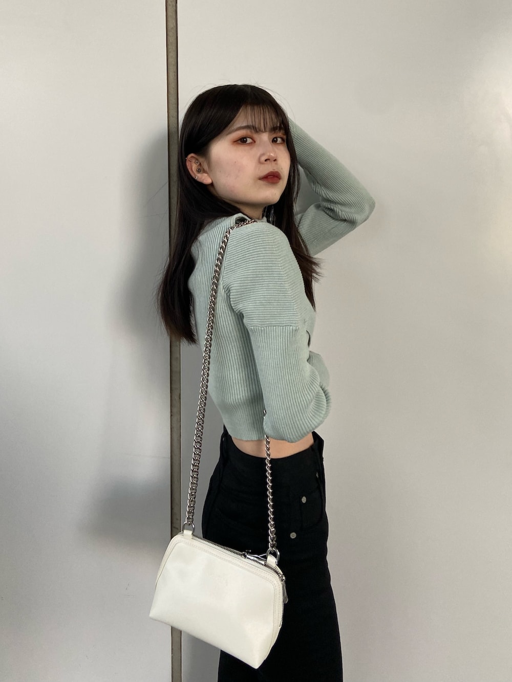 ブラック系のデニムパンツ、ブルー系のニット/セーター、ホワイト系のハンドバッグを着用したレディースの冬コーディネートの5枚目の写真