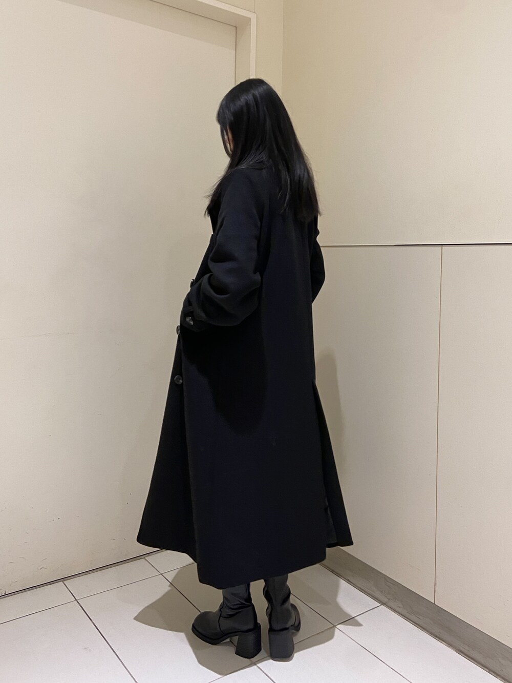 グリーン系のニット/セーター、ブラック系のチェスターコート、ブラック系のスカートを着用したレディースの冬コーディネートの3枚目の写真