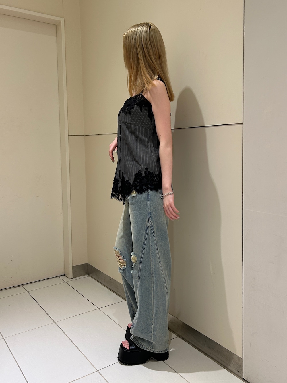 ブルー系のデニムパンツ、ブラック系のブーツ、グレー系のキャミソールを着用したレディースの春コーディネートの2枚目の写真