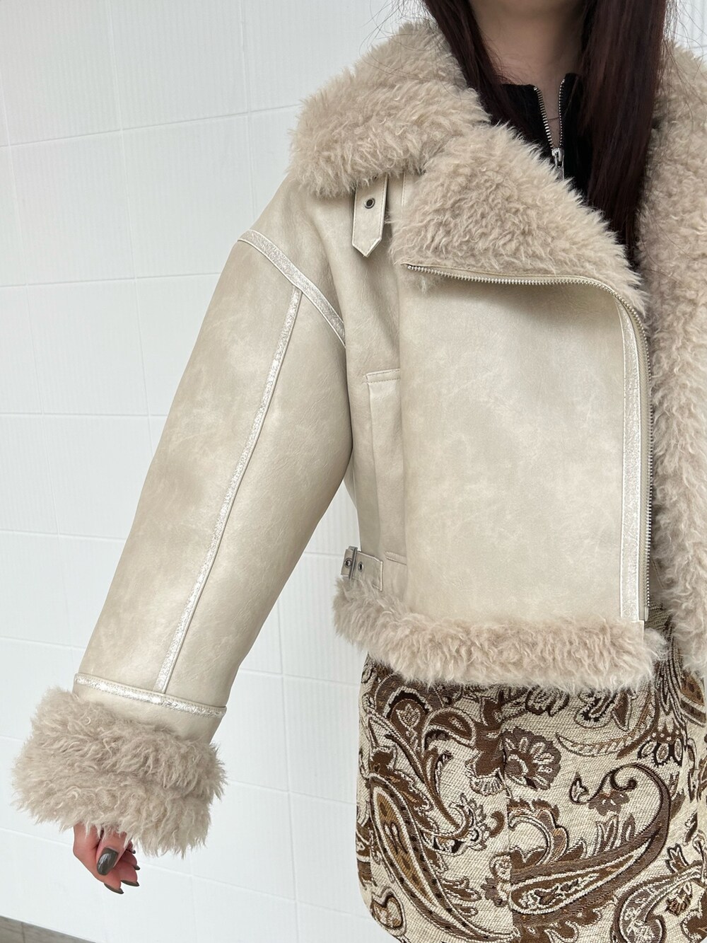 ホワイト系のスカート、ブラック系のニット/セーター、ホワイト系のムートンコートを着用したレディースの秋コーディネートの5枚目の写真