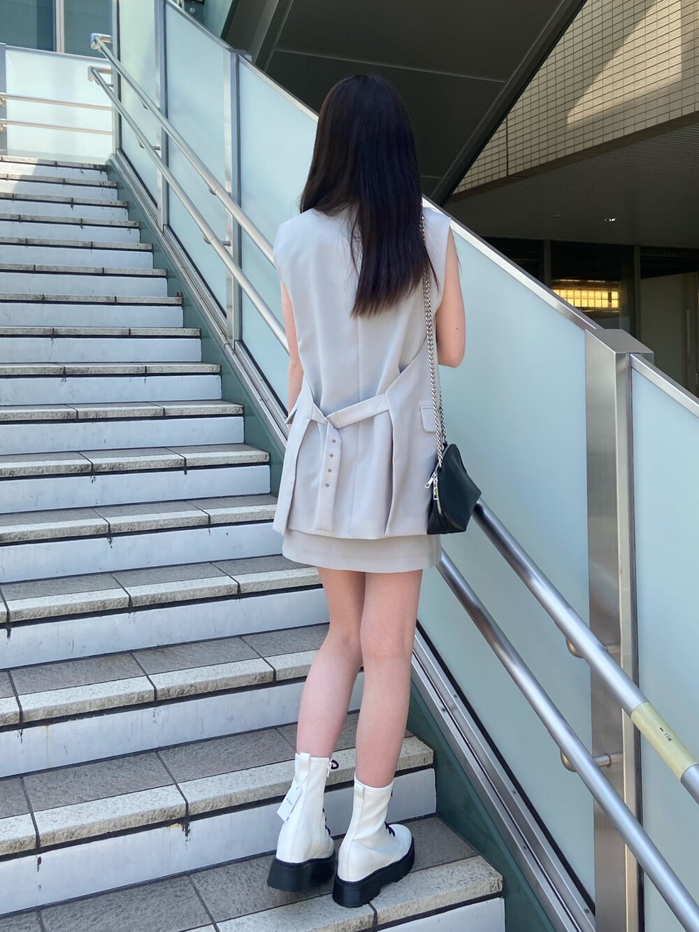 ブルー系のニット/セーター、グレー系のベスト、グレー系のスカートを着用したレディースの春コーディネートの3枚目の写真