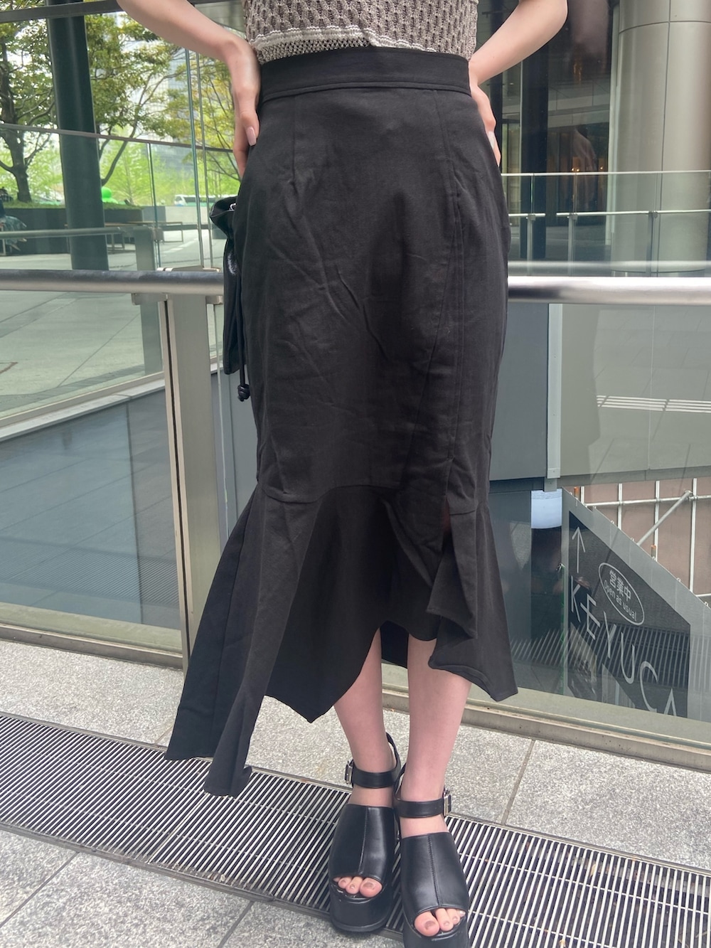グレー系のニット/セーター、ブラック系のスカート、ブラック系のサンダルを着用したレディースの春コーディネートの5枚目の写真