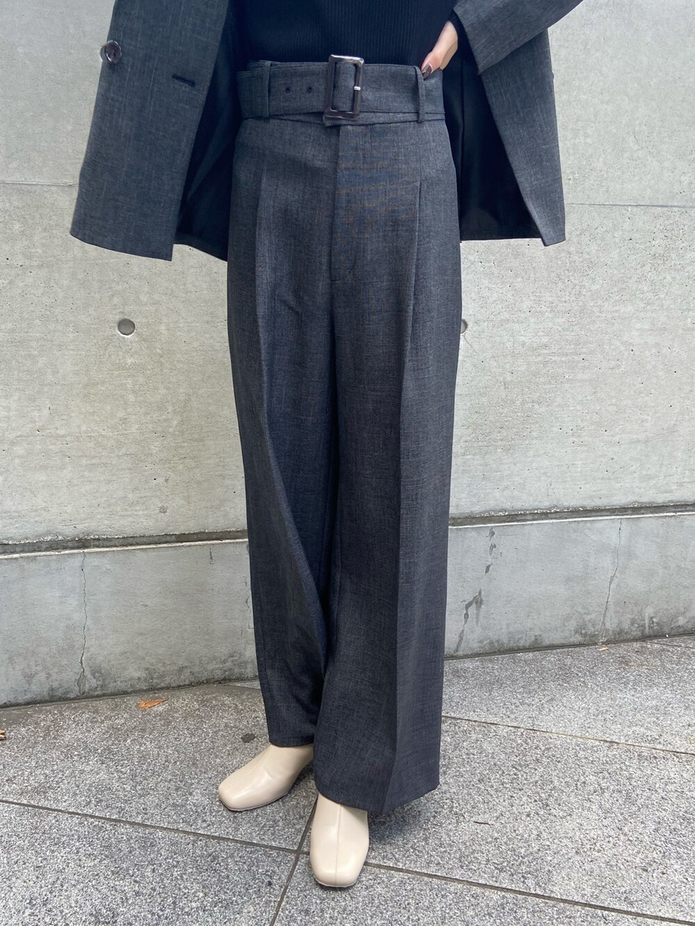 グレー系のテーラードジャケット、ブラック系のニット/セーター、グレー系のスラックスを着用したレディースの秋コーディネートの6枚目の写真