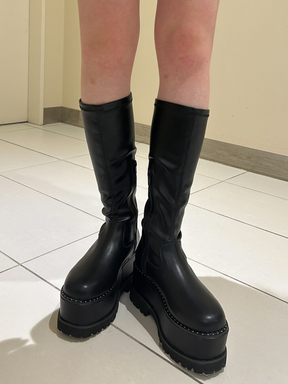 グリーン系のTシャツ/カットソー、ブラック系のスカート、ブラック系のブーツを着用したレディースの秋コーディネートの5枚目の写真