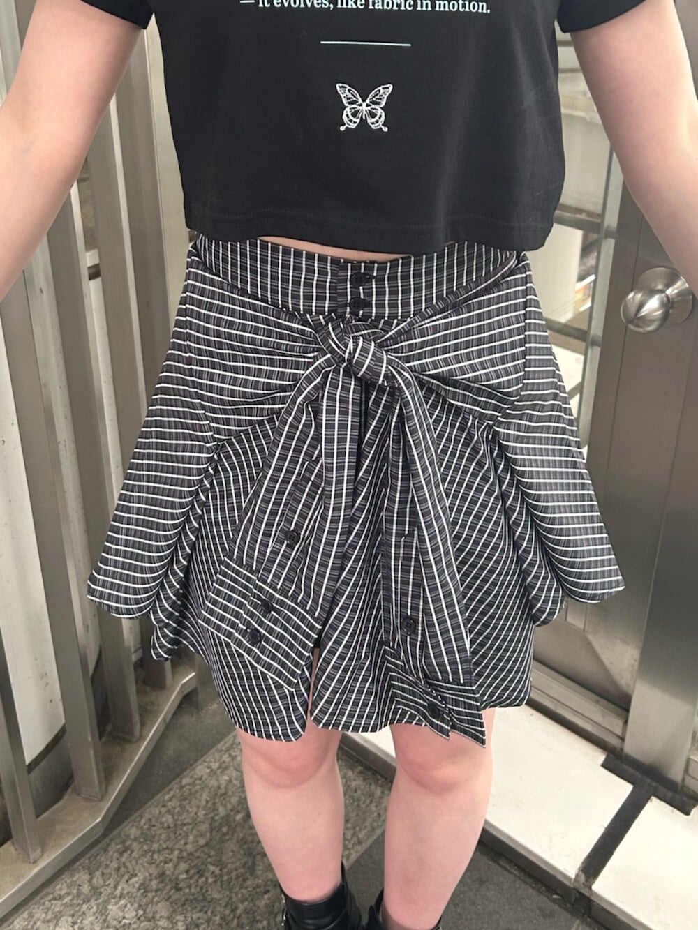 ブラック系のブーツ、ブルー系のスカート、ブラック系のTシャツ/カットソーを着用したレディースの夏コーディネートの5枚目の写真