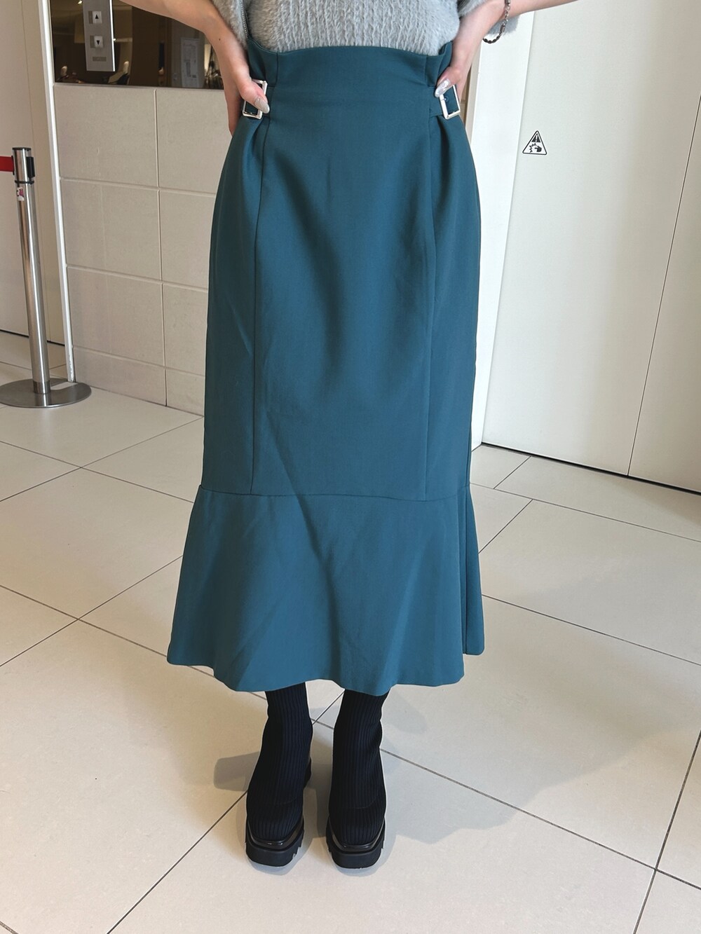 ブルー系のスカート、グレー系のニット/セーター、ブラック系のブーツを着用したレディースの秋コーディネートの5枚目の写真