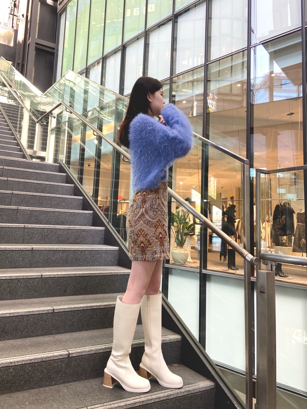 ブルー系のスカート、ブルー系のニット/セーター、ホワイト系のブーツを着用したレディースの秋コーディネートの2枚目の写真