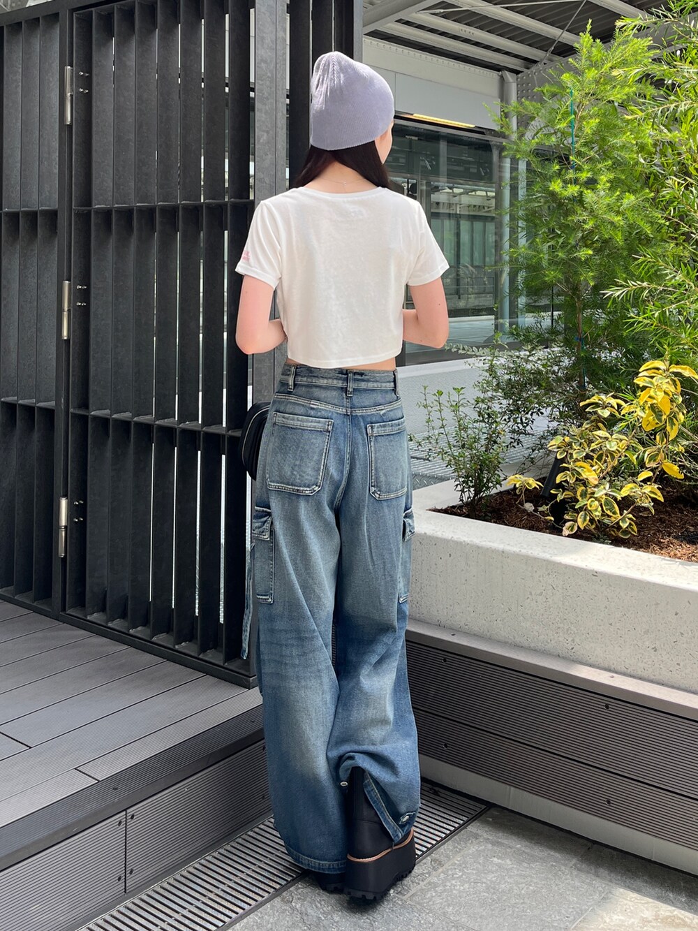 ブルー系のデニムパンツ、ホワイト系のTシャツ/カットソー、ブラック系のボストンバッグを着用したレディースの夏コーディネートの3枚目の写真