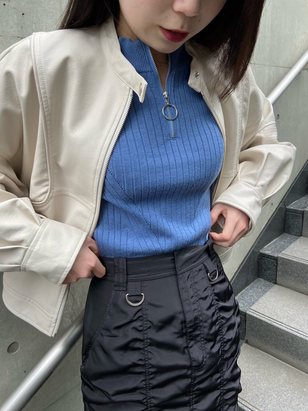 ブラック系のスカート、ブルー系のニット/セーター、ホワイト系のブルゾンを着用したレディースの春コーディネートの5枚目の写真