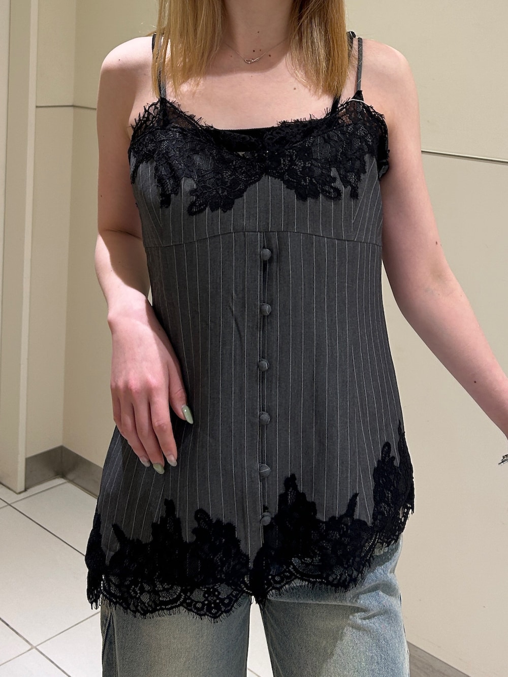 ブルー系のデニムパンツ、ブラック系のブーツ、グレー系のキャミソールを着用したレディースの春コーディネートの4枚目の写真