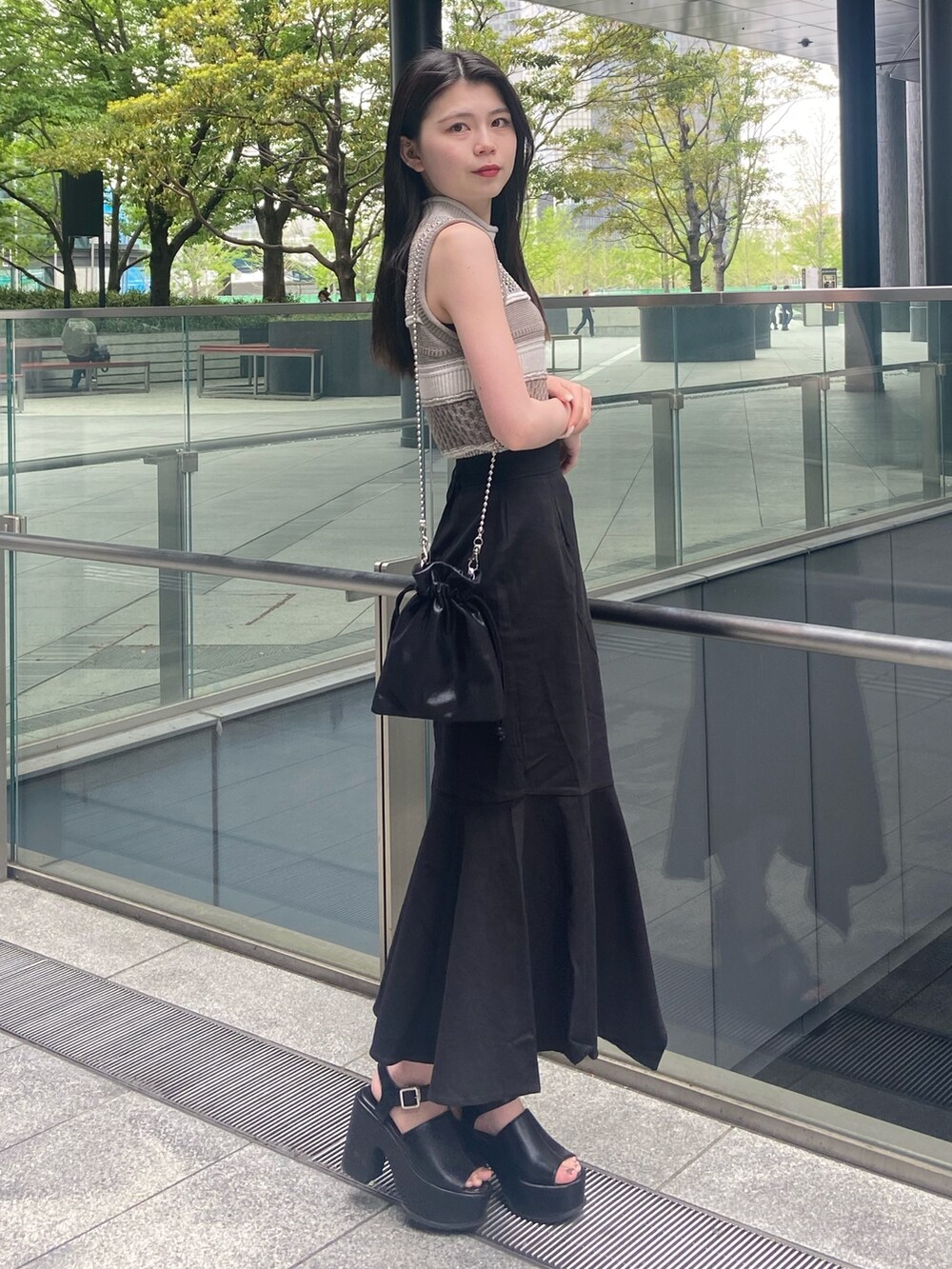 グレー系のニット/セーター、ブラック系のスカート、ブラック系のサンダルを着用したレディースの春コーディネートの2枚目の写真