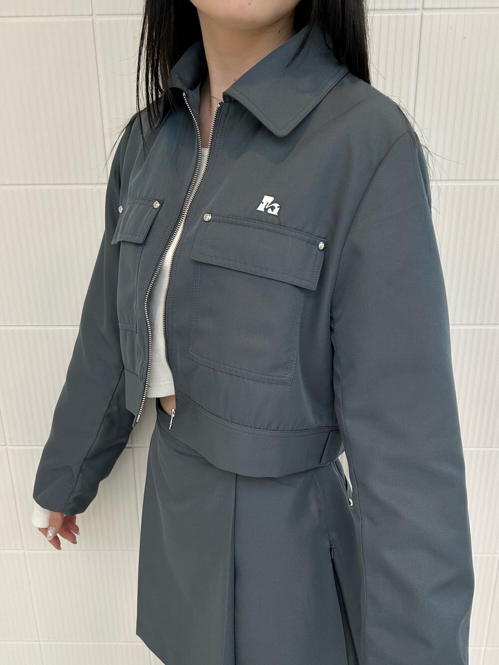 グレー系のスカート、グレー系のブルゾン、ホワイト系のTシャツ/カットソーを着用したレディースの春コーディネートの5枚目の写真