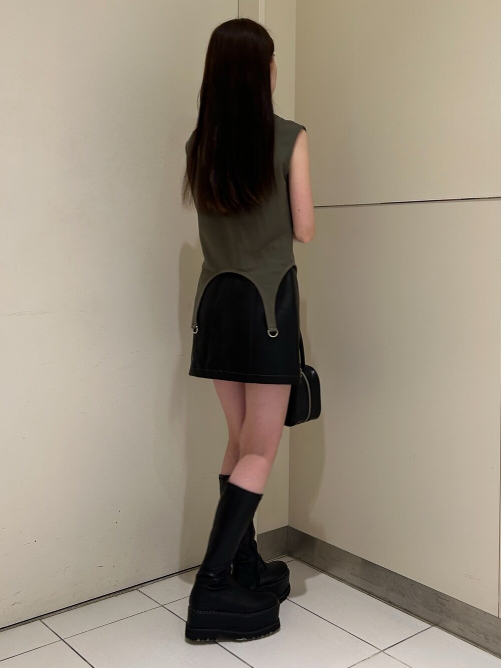 グリーン系のTシャツ/カットソー、ブラック系のスカート、ブラック系のブーツを着用したレディースの秋コーディネートの3枚目の写真