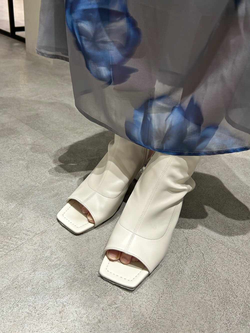 ブラック系のニット/セーター、グレー系のスカート、ホワイト系のブーツを着用したレディースの春コーディネートの6枚目の写真