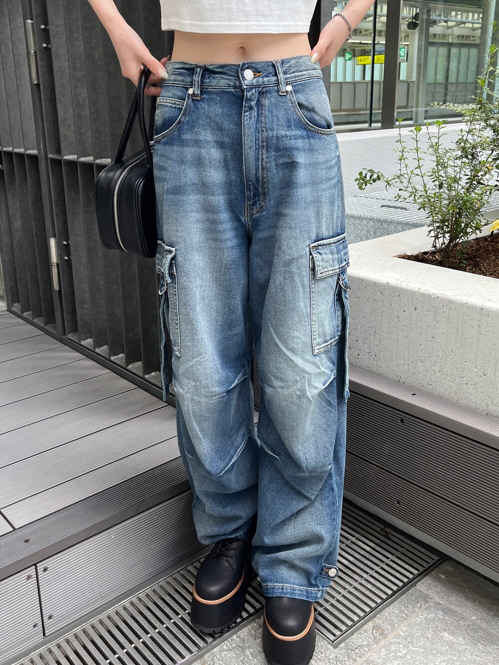 ブルー系のデニムパンツ、ホワイト系のTシャツ/カットソー、ブラック系のボストンバッグを着用したレディースの夏コーディネートの6枚目の写真