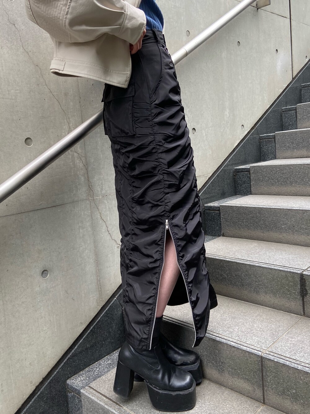 ブラック系のスカート、ブルー系のニット/セーター、ホワイト系のブルゾンを着用したレディースの春コーディネートの7枚目の写真